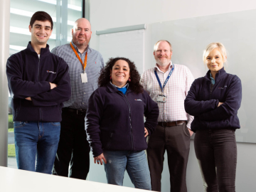 A group of smiling people standing in front of a white wall