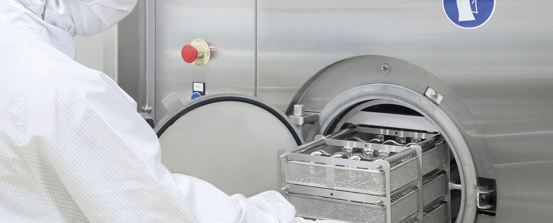 A worker in front of a cleaning and disinfecting machine preparing an order for cleaning. 