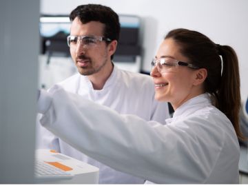 Two laboratory workers in front of a monitor